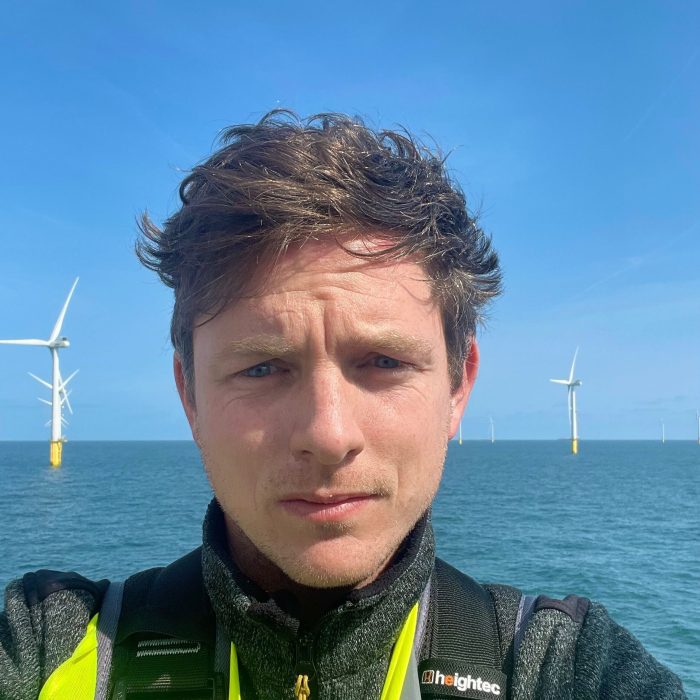 Portrait shot of Jack Hughleigh in front of offshore windfarm